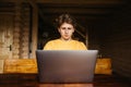 Young man in casual clothes sitting at a wooden table in the country and working on a laptop. Work on the Internet Royalty Free Stock Photo