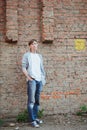 Young man  in casual clothing standing in full size near brick wall background Royalty Free Stock Photo