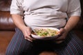 a fat men in casual dress eating fresh salad , healthy food concept