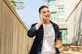 A young man in a casual outfit with a jacket, walking outdoors, talking on a mobile phone Royalty Free Stock Photo