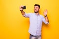 Young man in casual outfit taking a picture of himself, using smart phone, having video call with friends, sending greetings with Royalty Free Stock Photo