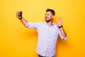 Young man in casual outfit taking a picture of himself, using smart phone, having video call with friends, sending greetings with Royalty Free Stock Photo