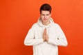 Young man in casual style hoodie pressing hands together showing namaste gesture, practicing yoga with peacefull face and closed