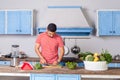 Young man in casual t-shirt chopping cutting vegetables, preparing vegetarian salad in modern kitchen Royalty Free Stock Photo