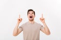 Young man in casual t-shirt looking upwards with pointing finger Royalty Free Stock Photo