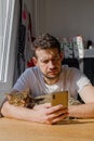 A young man with a cat in his arms looks into the phone at an incoming sms. Royalty Free Stock Photo