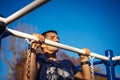 A young man of Caucasian appearance pulls himself up on a horizontal bar.