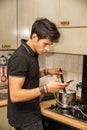 Young Man with Cell Phone Cooking Food on Stove Royalty Free Stock Photo