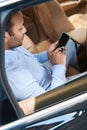 Young man with cellphone sitting in automobile