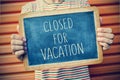 Young man with a chalkboard with the text closed for vacation, f