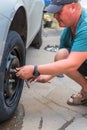 A young man changes a flat tire on a car on a summer day