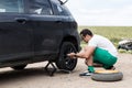 Young man changing the punctured tyre on his car