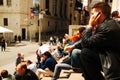 A young man chats on the phone while sitting at Wall Street