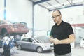 Young man with a check list for a car revision. Repair workshop with empty copy space Royalty Free Stock Photo