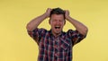 Young man in checkered shirt putting fists on head and screaming in pain Royalty Free Stock Photo