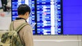 Young man checking timetable over airline billboard for travel at the airport