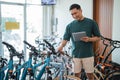 young man checks the handlebars of a bicycle while using a tablet