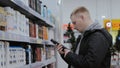 A young man chooses hair care products. A man chooses a hygiene product. Buying shampoo in the supermarket. Body care Royalty Free Stock Photo