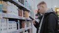 A young man chooses a shampoo. A man chooses a hygiene product. Buying shampoo in the supermarket. Body care products Royalty Free Stock Photo