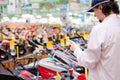 Young man choosing and photographing on the tablet pc computer lawnmowers in garden tools department of DIY shopping store Royalty Free Stock Photo