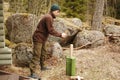 Young man chops wood with an ax in the forest. Guy chops a tree into logs with an cleaver in natura