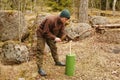 Young man chops wood with an ax in the forest. Guy chops a tree into logs with an cleaver in natura