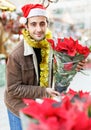 Young man in Christmas hat buying flowers and decoration at Christmas fair Royalty Free Stock Photo