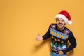 Young man in Christmas sweater and hat on color background