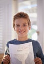 This young man is chuffed with himself. a proud young boy holding up his essay that got him an A. Royalty Free Stock Photo