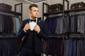 Young man in classic vest against row of suits in shop