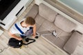 Young Man Cleaner Sofa With Vacuum Cleaner