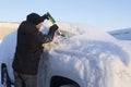 Young man cleaning car from snow