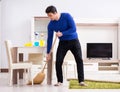 Young man cleaning floor with broom