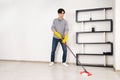 A young man cleaning the floor with a mop