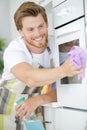 Young man cleaning oven in kitchen Royalty Free Stock Photo
