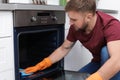 Young man cleaning oven with rag Royalty Free Stock Photo