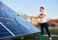 Young guy is cleaning solar panel on a plot near the house Royalty Free Stock Photo