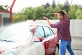 Young man cleaning vehicle with high pressure foam jet