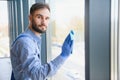 Young man cleaning window in office Royalty Free Stock Photo