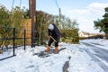 A young man clearing the footpath of snow and ice to make it safe to walk on during a heavy snowfall. Winter safety, clearing snow Royalty Free Stock Photo