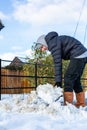 A young man clearing the footpath of snow and ice to make it safe to walk on during a heavy snowfall. Winter safety, clearing snow Royalty Free Stock Photo