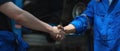 Young man client shaking hands with auto mechanic in red uniform having a deal at the car service Royalty Free Stock Photo