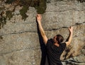 Young man climber climb on rock in small crack stone