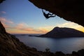 Young man climbing along ceiling of cave at sunset