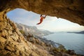 Young man climbing challenging route in cave against view of coast Royalty Free Stock Photo