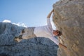 Young man climbing rock wall and hanging above gap