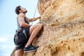 Young man climbing a steep wall in mountain