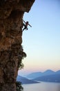 Young man climbing vertical cliff at sunset Royalty Free Stock Photo