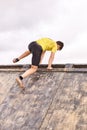 Young man climbing a wooden wall in a Spartan race