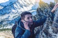 A young man climbs the mountain to the top and talking holding the phone. Concept of persistence and goal achievement Royalty Free Stock Photo